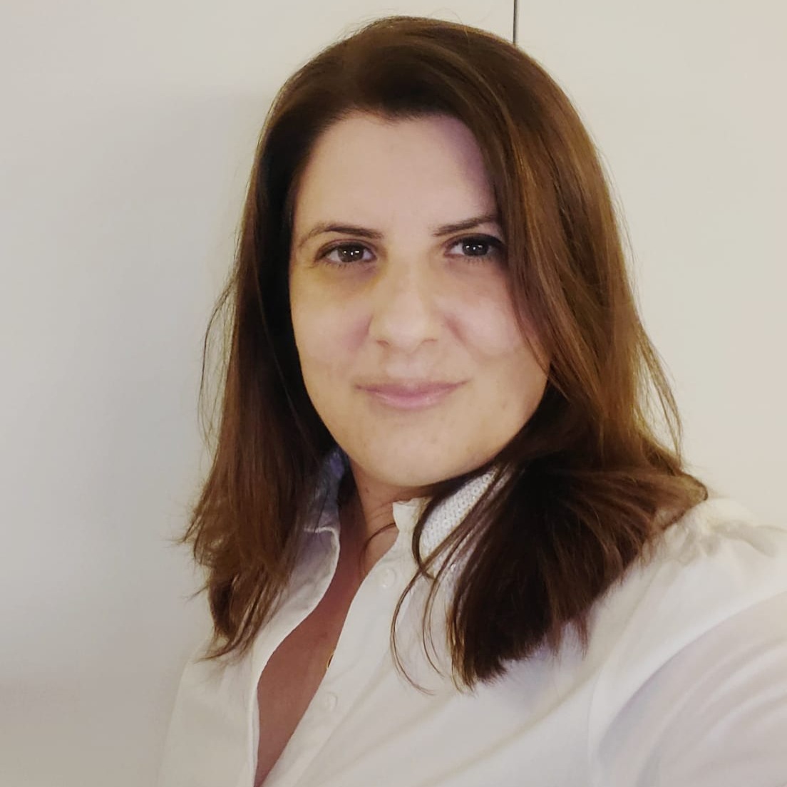 Foto de Nadia Hage, com cabelos longos e castanhos, sorrindo e olhando diretamente para a câmera.