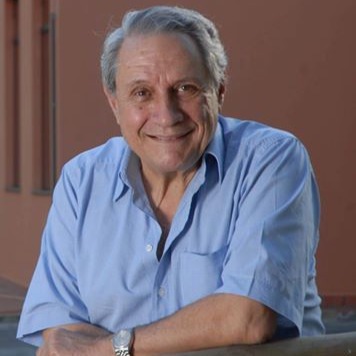 Foto de Sylvio Rosa, com cabelos curtos e escuros, sorrindo e olhando diretamente para a câmera.